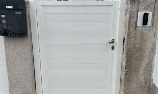 Moderne, weiße Eingangstür mit elektronischer Gegensprechanlage und Briefkasten.