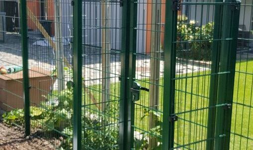 Grüner Metallzaun mit Maschendraht, passend für Garteneinfriedungen.