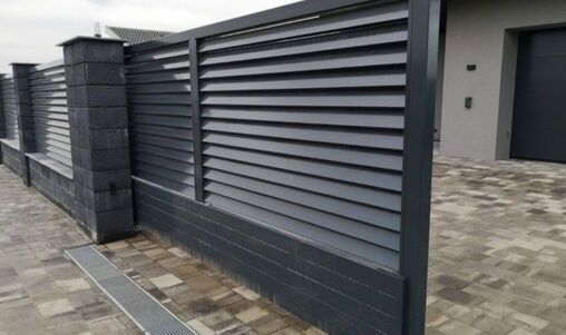 Moderner Metallzaun mit horizontalen Lamellen, in dunklem Farbton, passend für Grundstücke.