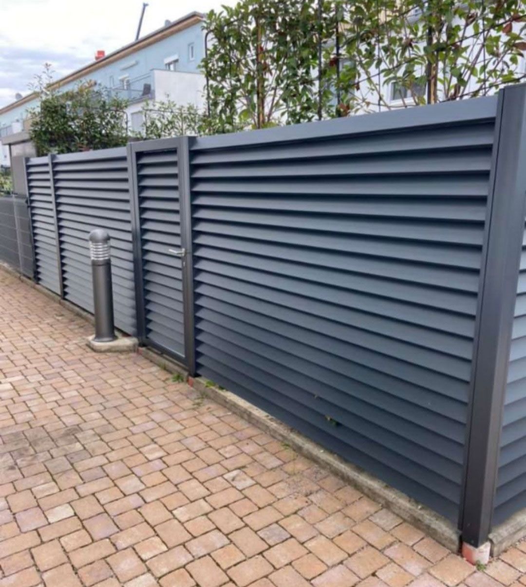 Dunkelgrauer Zaun mit horizontalen Lamellen, modern gestaltet.